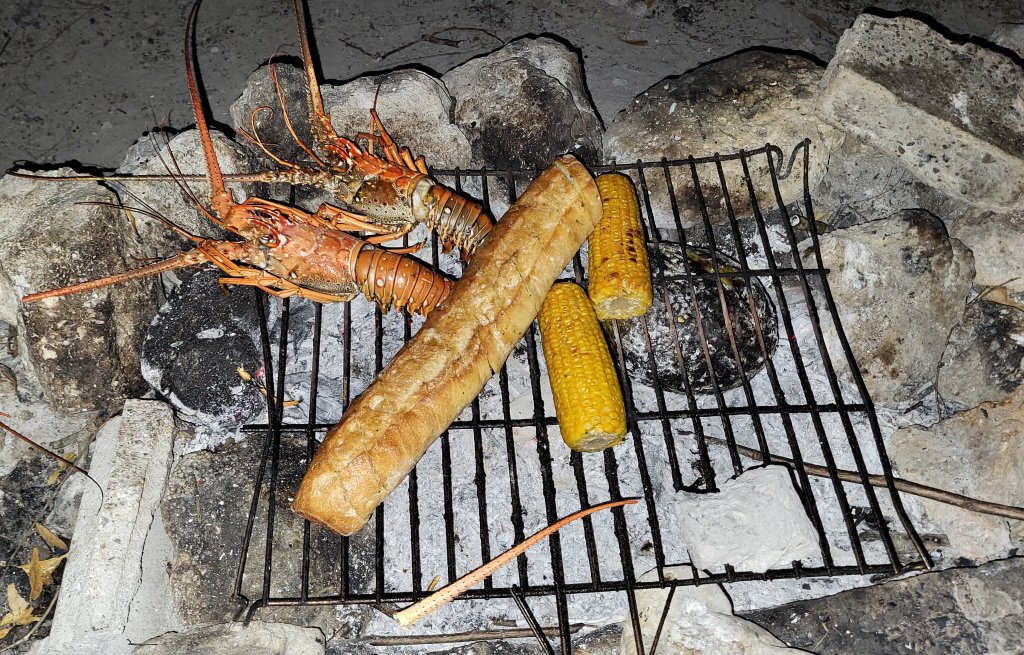 Lobster, Knoblibrot, Mais und eine schwarze Brotfrucht.