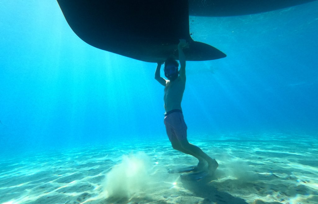 Der Captain stemmt das Boot im kristallklaren Wasser von Kefalonia.