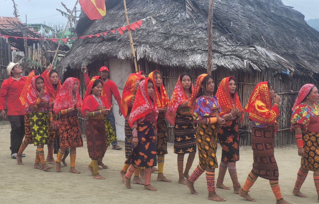 They march through their village in traditional clothing.